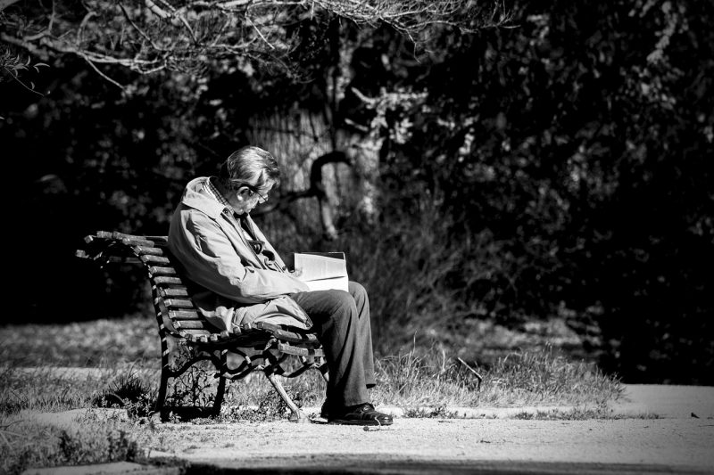 Melancholia. Mężczyzna siedzacy na ławce z książką.