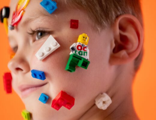 dziecko z klockami lego na twarzy