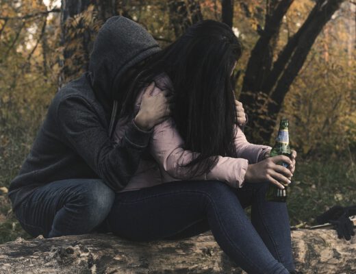 Kobit z problemem alkoholowym siedzi w lesie i pije piwo